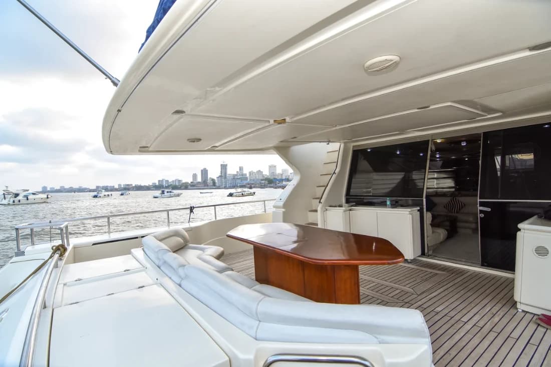 Flybridge aft lounge seating and dining table beside the upper helm