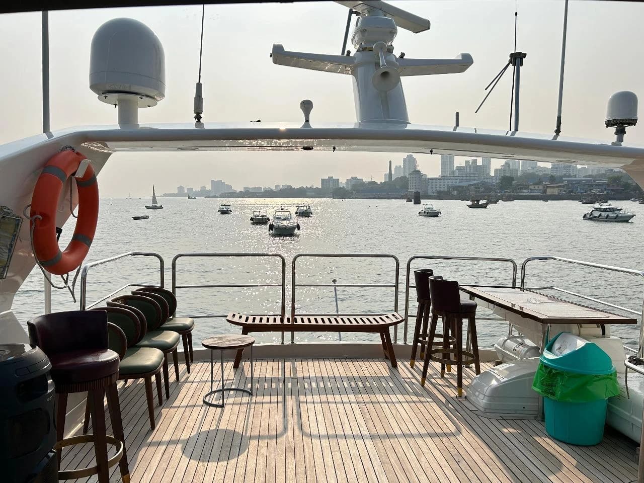 Flybridge bar stools and bench seating, with the Mumbai skyline and harbour behind