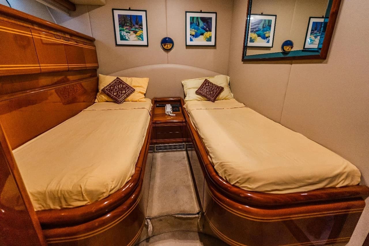 A second twin-bed cabin with cream bed linen and a porthole
