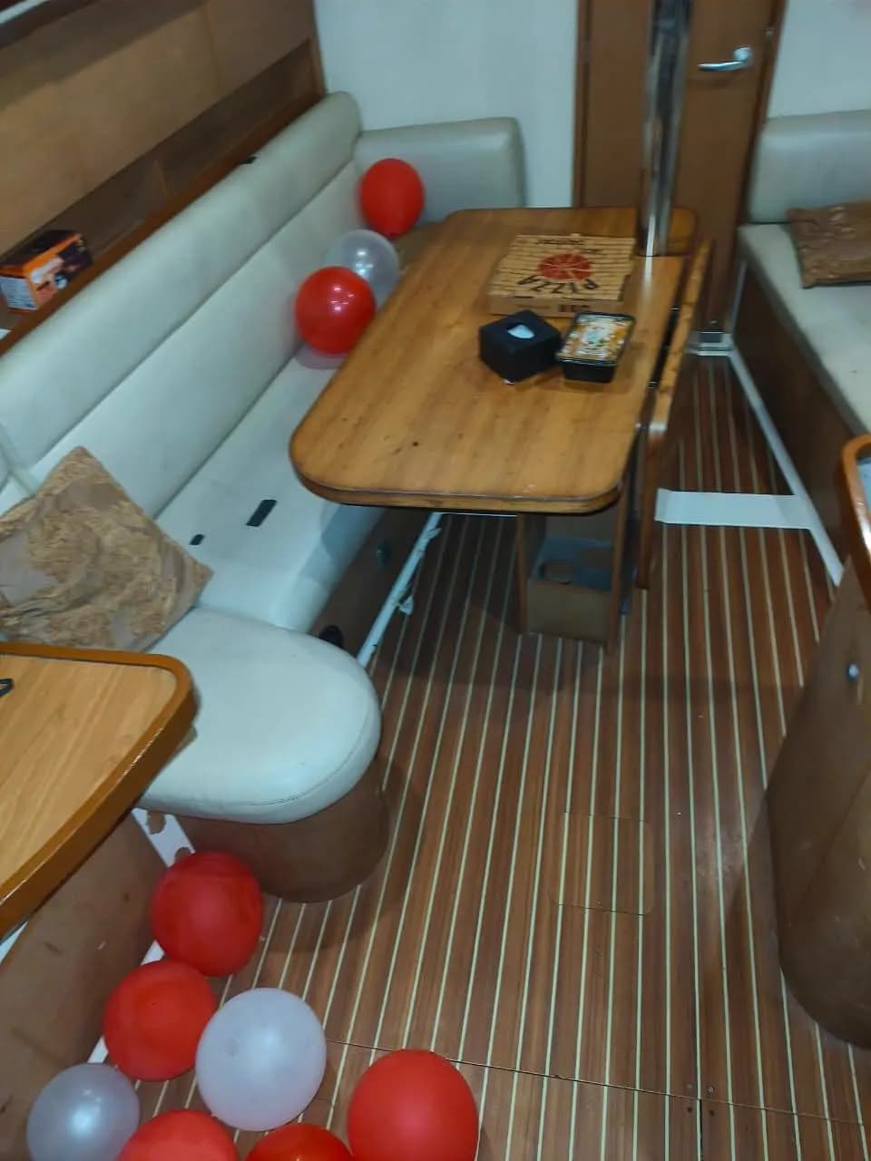 Pizza and snacks laid out on the saloon table, decorated with red and silver balloons