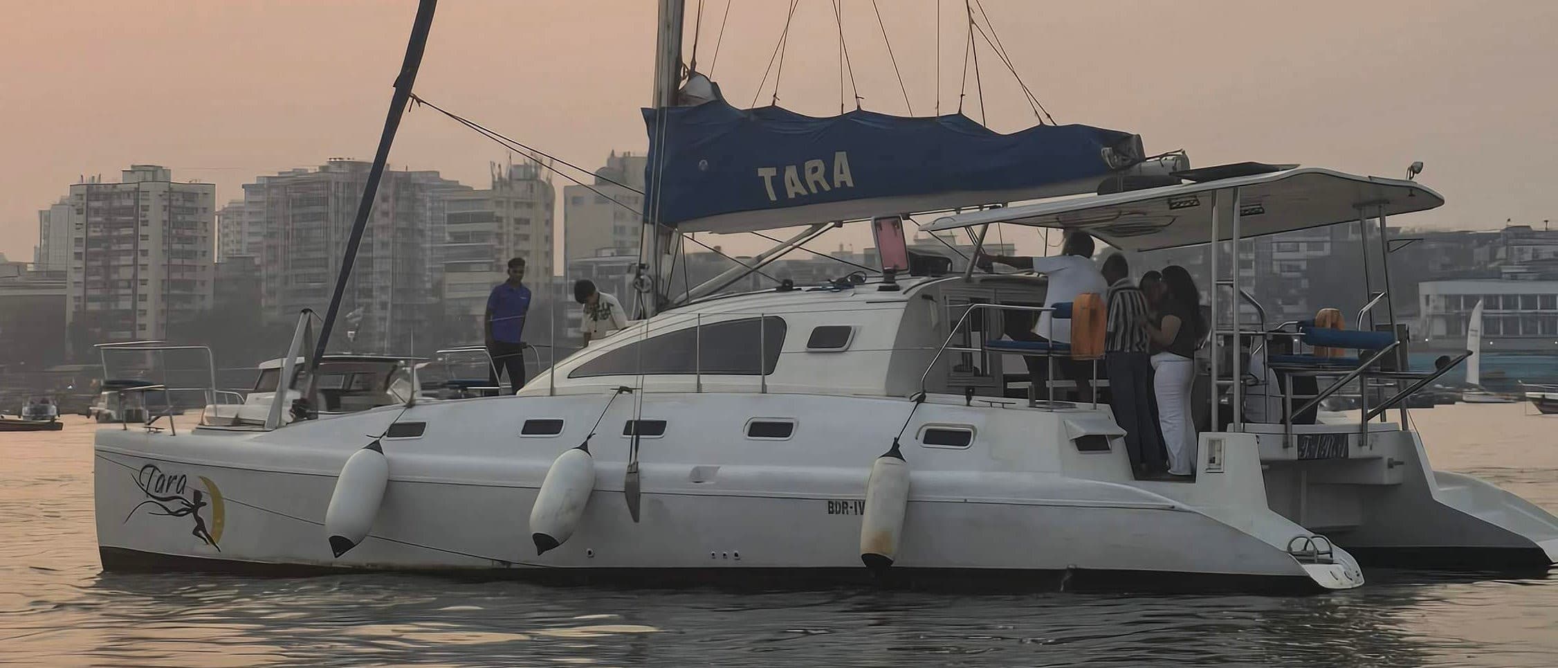 Tara, a sailing catamaran, under way past the Middle Ground coastal battery with the Mumbai skyline behind