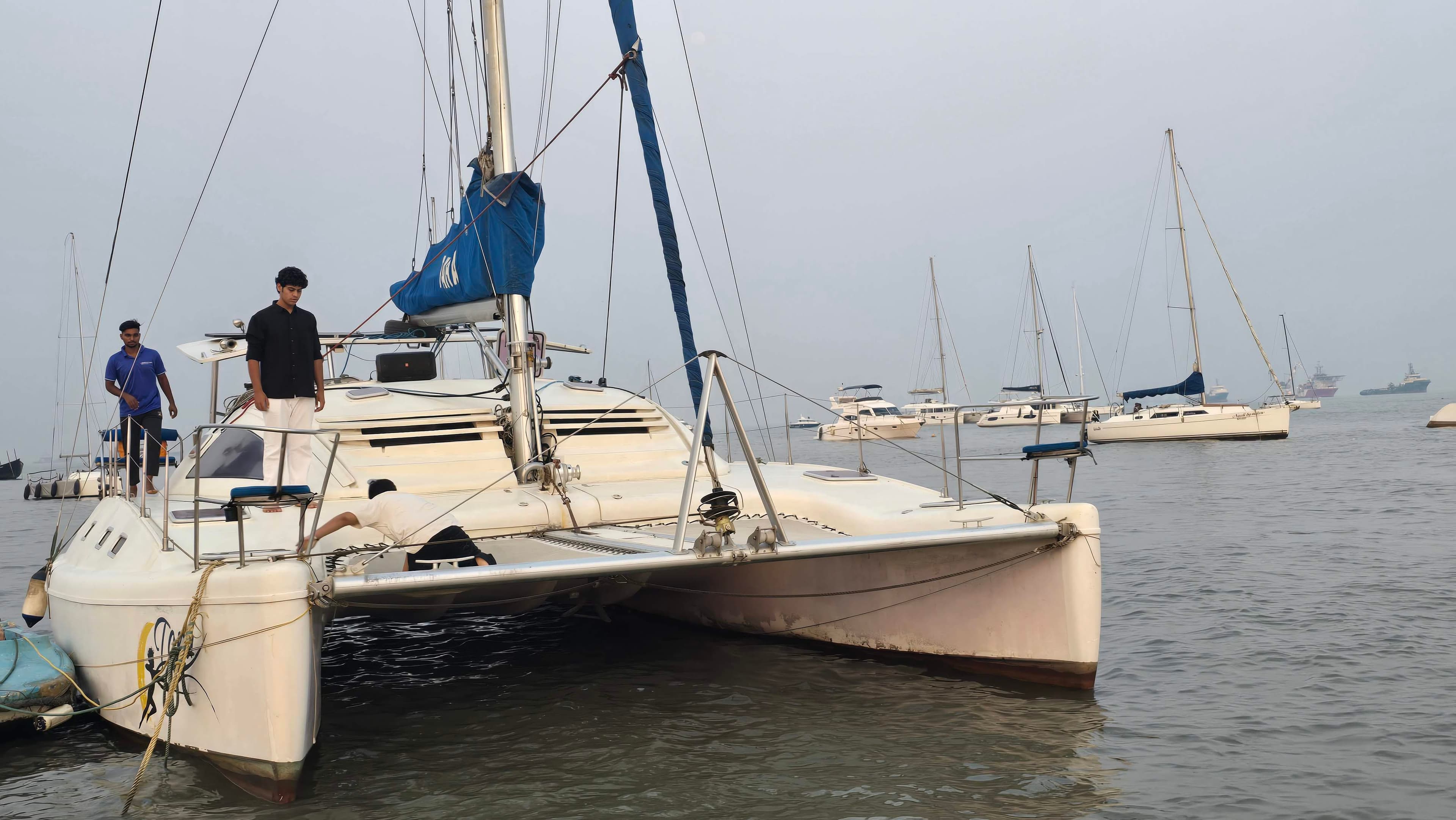 Crew preparing Tara's bow among moored yachts in the anchorage