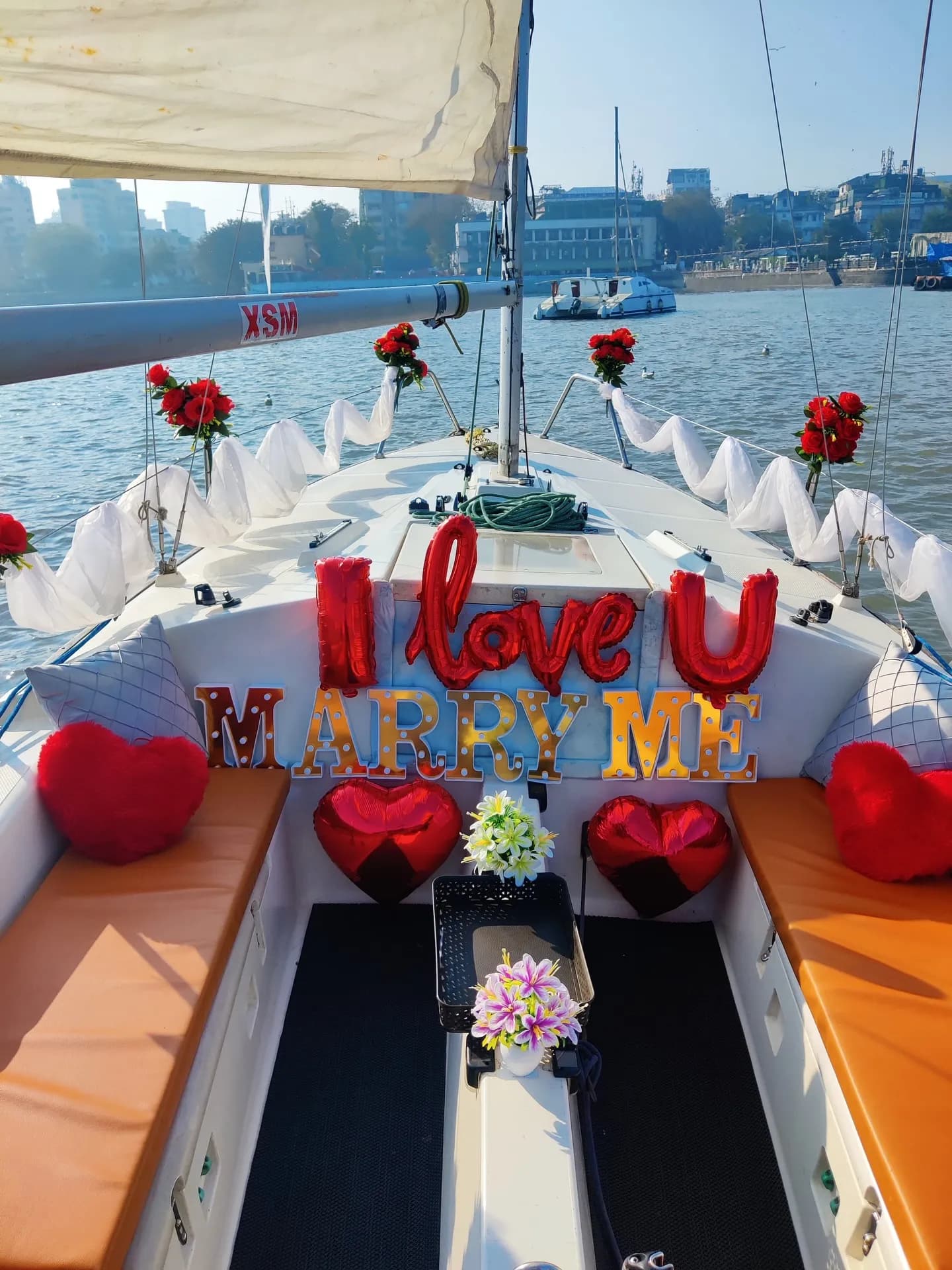 An 'I Love U, Marry Me' balloon proposal display at the bow with red hearts and roses