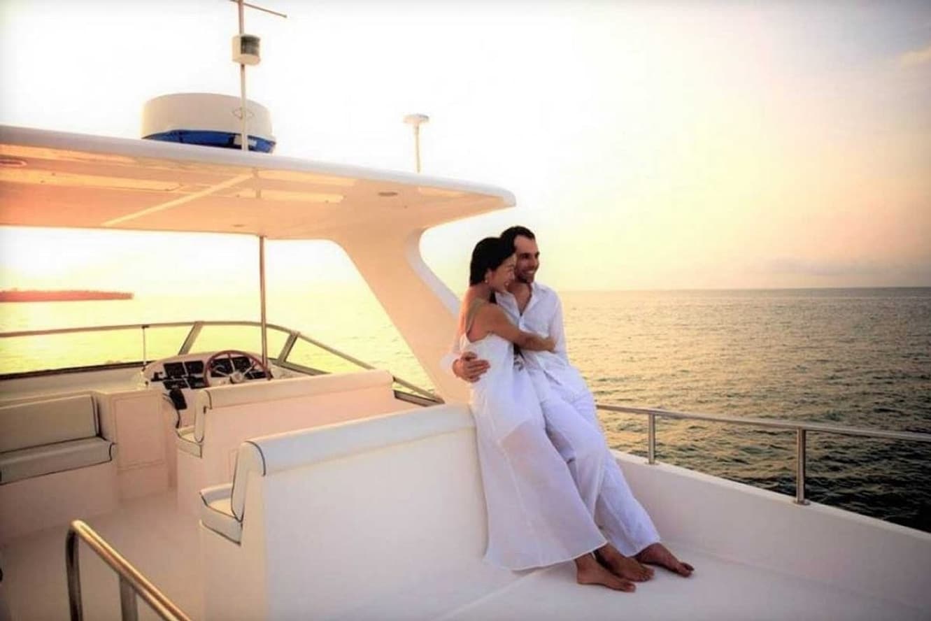 A couple embracing on the flybridge deck of a motor yacht at sunset